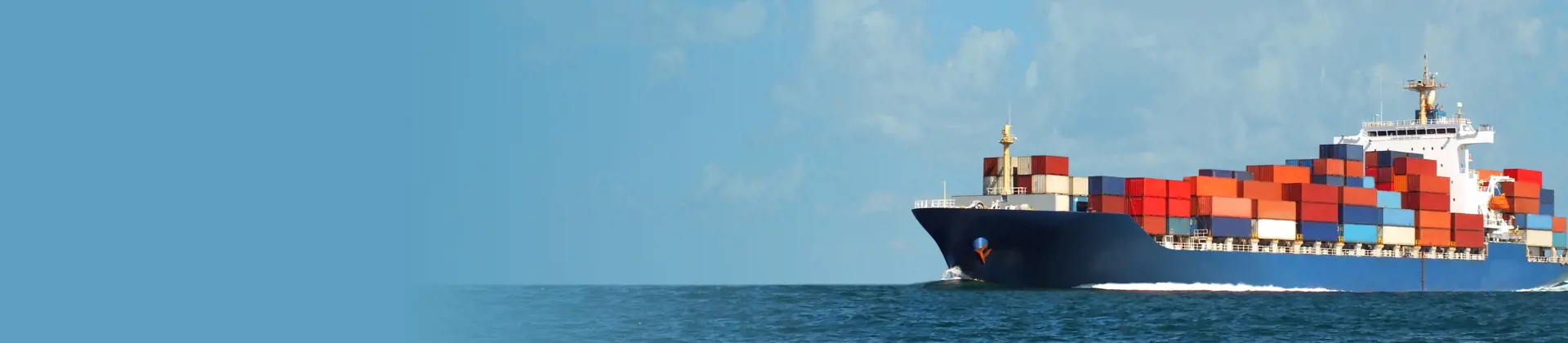 Large cargo ship transporting stacked shipping containers across a calm ocean under a clear sky.