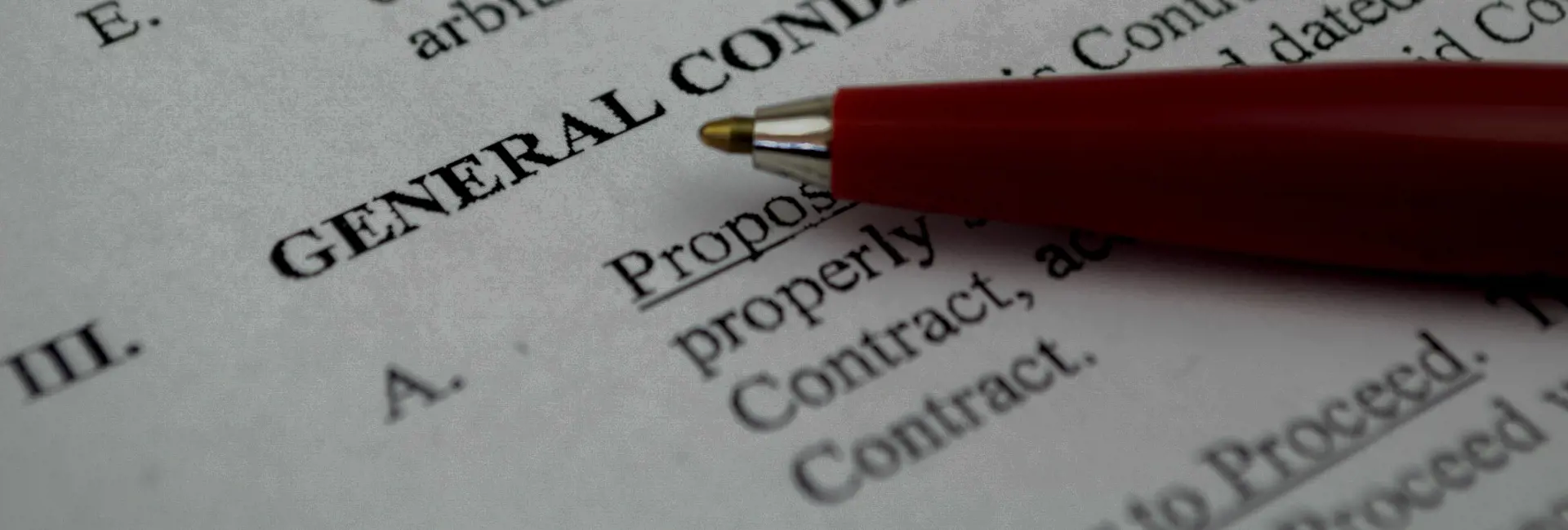 Close-up of a document with the heading 'General Conditions' and a red pen pointing to the text