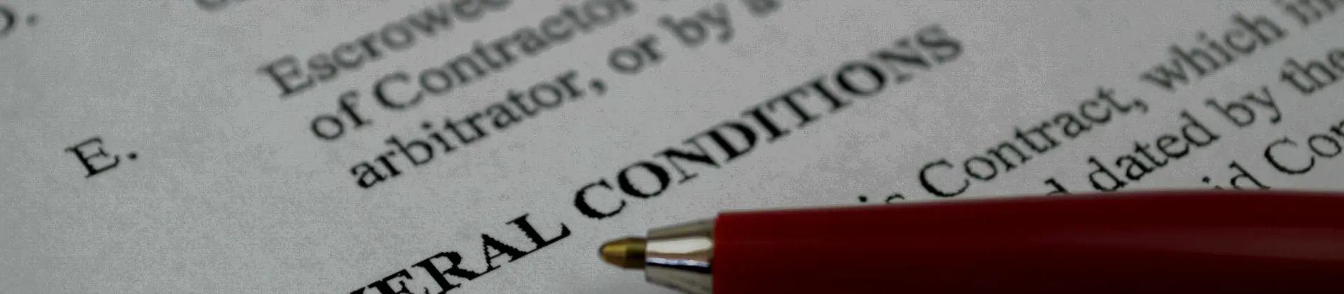 Close-up of a document with the heading 'General Conditions' and a red pen pointing to the text