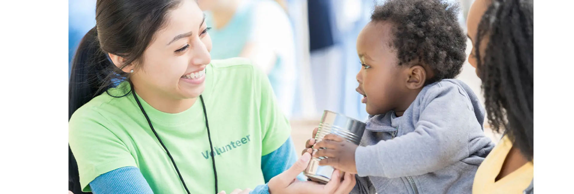Smiling volunteer handing a food can to a child, symbolizing Scan Global Logistics’ focus on humanitarian logistics