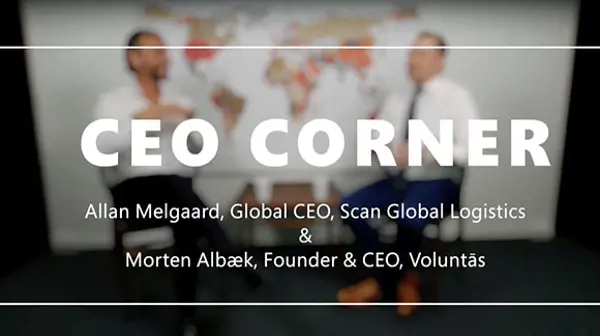 Text overlay reading 'CEO Corner: Allan Melgaard, Global CEO, Scan Global Logistics & Morten Albæk, Founder & CEO, Voluntás,' with two people blurred in the background seated in front of a world map
