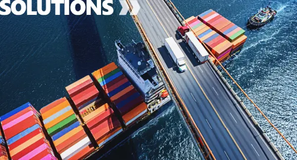 Container ship passing under a bridge as trucks transport cargo above, illustrating multimodal logistics solutions