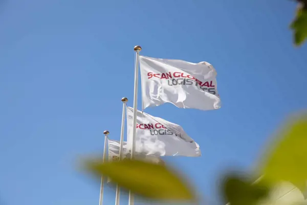 Flags with the Scan Global Logistics logo waving against a clear blue sky