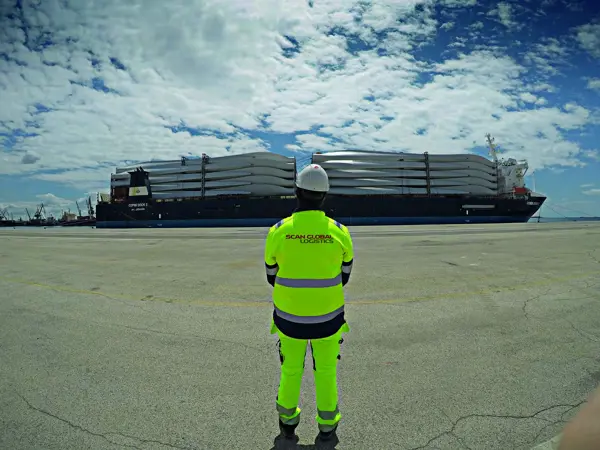 Scan Global Logistics employee overseeing a ship loaded with wind turbine components, symbolizing customer case successes.