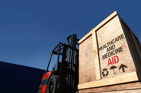 Forklift transporting a wooden crate labeled 'Healthcare and Medicine Aid,' representing Scan Global Logistics' humanitarian logistics expertise