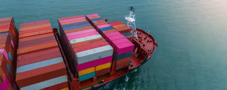 Container ship carrying colorful cargo containers across the ocean, representing Scan Global Logistics' sea freight services