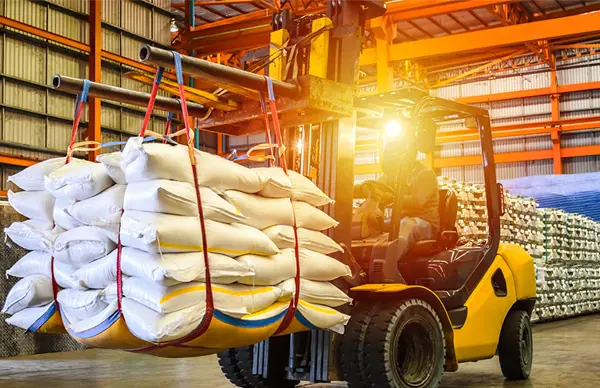 Forklift lifting bundled sacks in a brightly lit warehouse